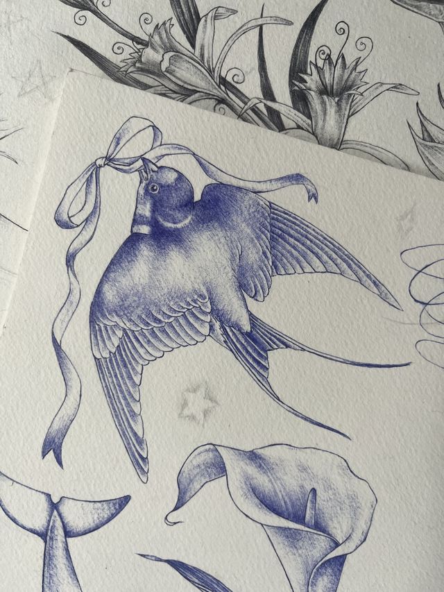Blue ballpoint flash — a swallow carrying a long ribbon in its beak, above calla lilies.