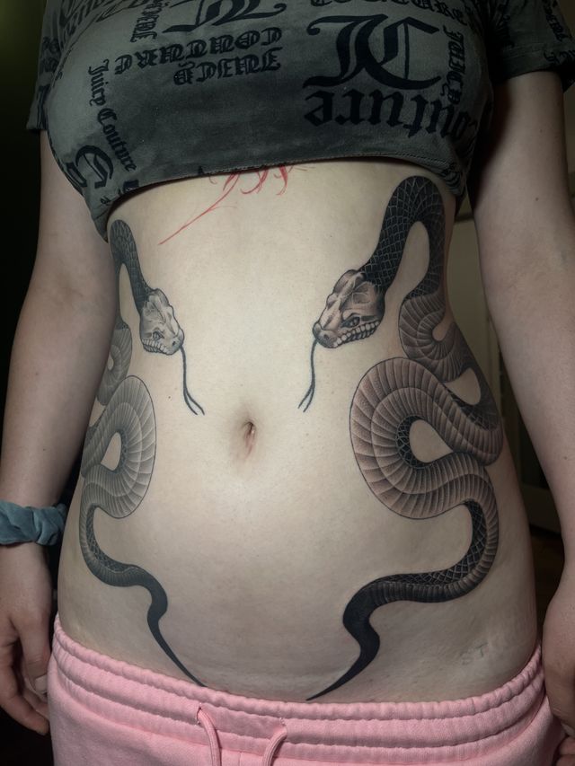 Two mirrored snakes curling across the stomach.